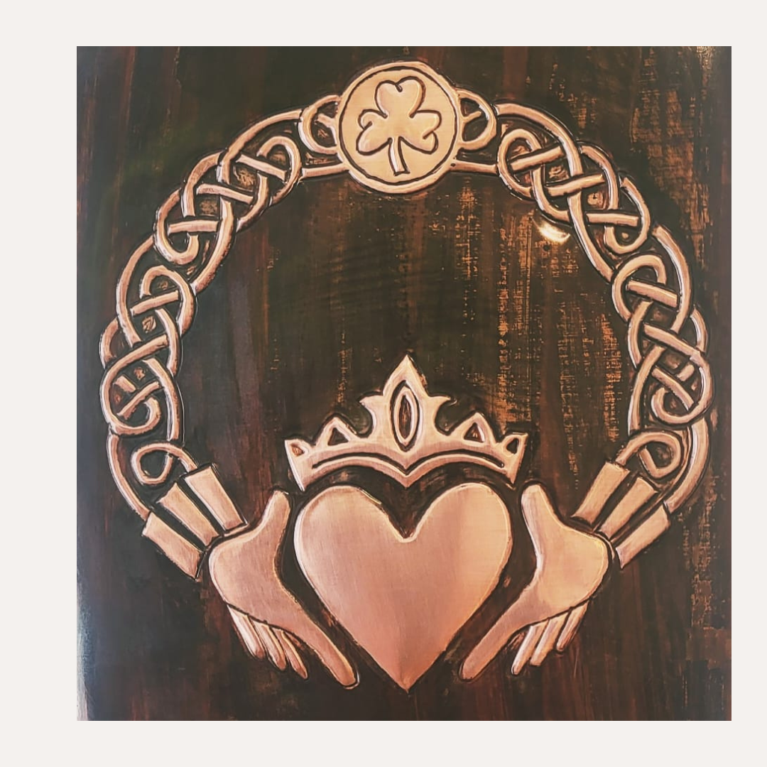 Handcrafted copper artwork featuring a traditional Claddagh design with a crowned heart and hands, surrounded by intricate Celtic knotwork, symbolizing eternal love, loyalty, and friendship.