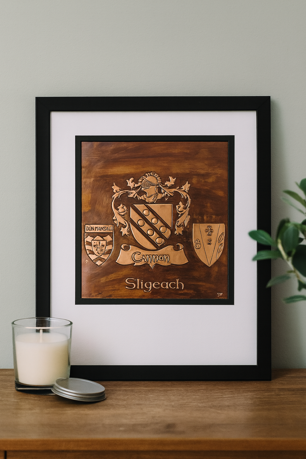Framed copper family crest artwork featuring the Cannon surname with Donegal and Sligo county shields, elegantly displayed on a softly lit interior wall as part of a cozy Irish-inspired home décor setting.